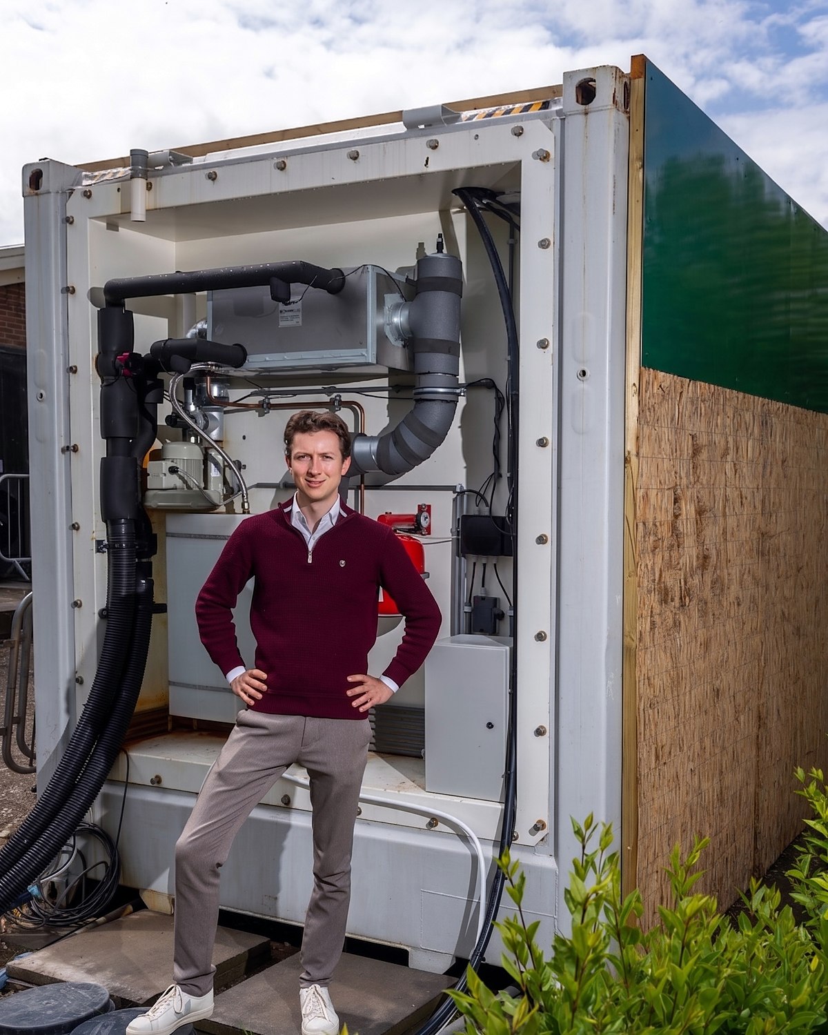 Nathan van den Dool bij de geopende container, met de installatie zichtbaar