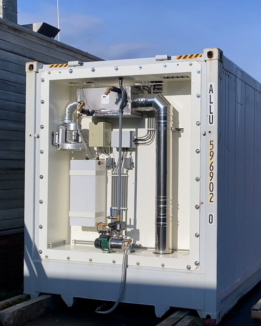 De machinekant van de container, met de warmtewisselaar en het leidingwerk
